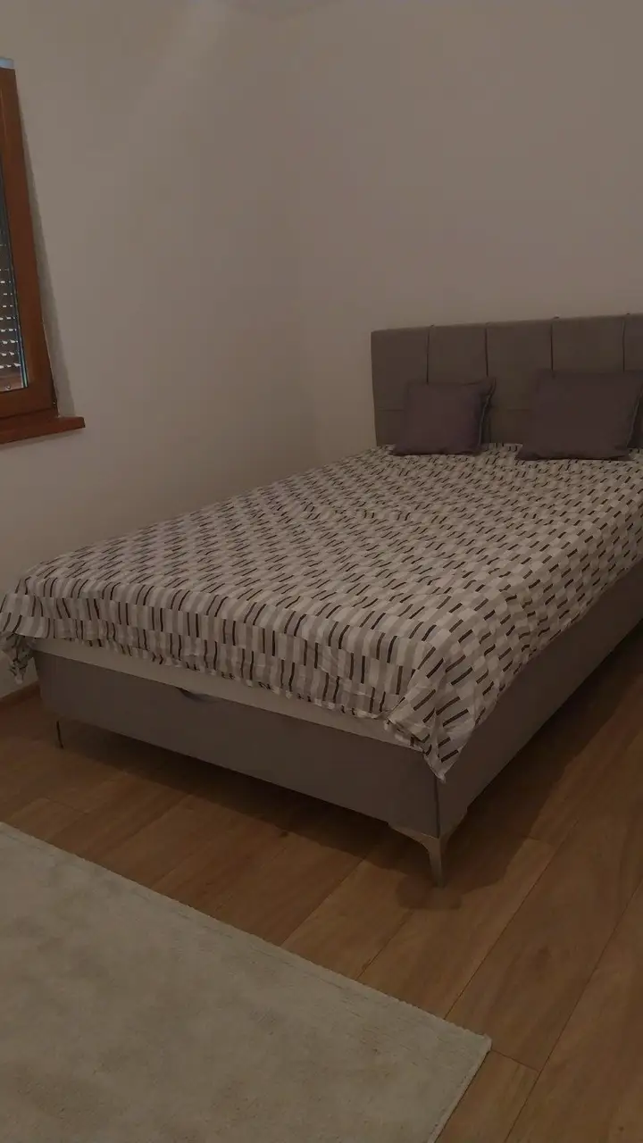 Sivi francuski ležaj s kvadratnim uzglavljem i prekrivačem u spavaćoj sobi