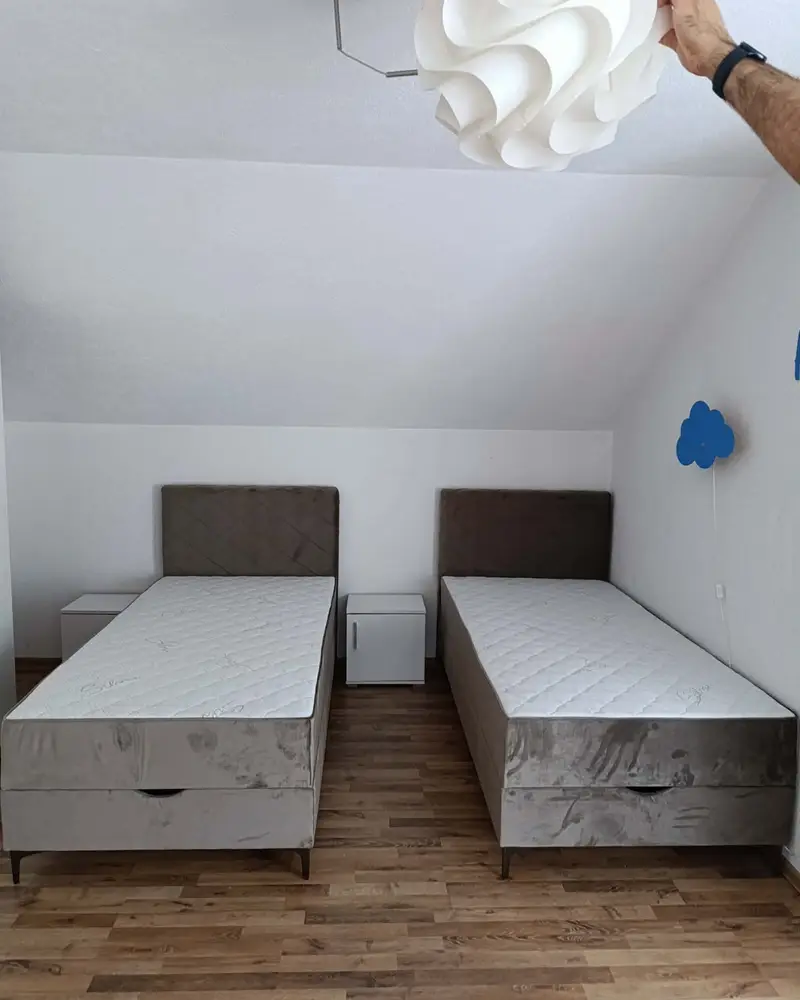 Dva jednokrevetna ležaja sa smeđim uzglavljem u dječijoj sobi